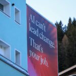Red billboard reading AI can't lead change. That's your job in a mountain town