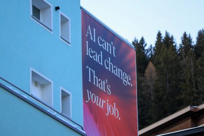 Red billboard reading AI can't lead change. That's your job in a mountain town