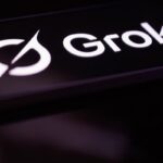 Grok logo glowing on a smartphone screen in a dark room