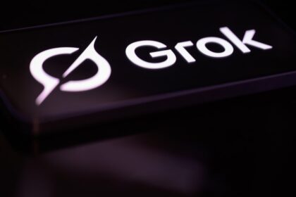Grok logo glowing on a smartphone screen in a dark room
