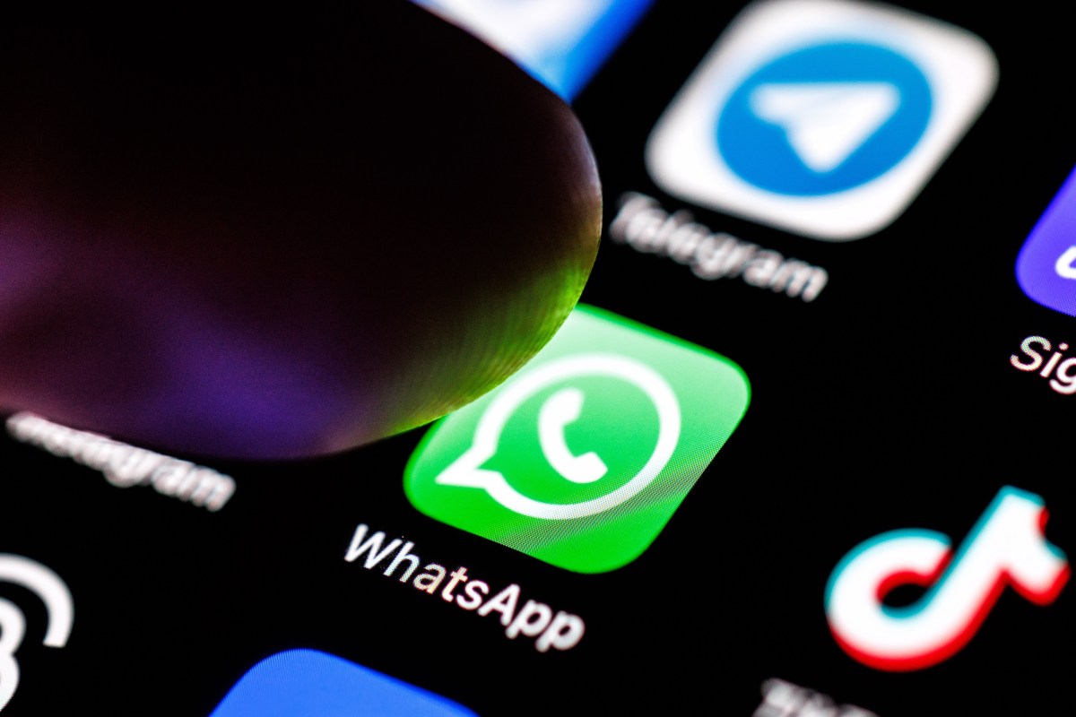 iPhone showing the WhatsApp app icon on a wooden desk