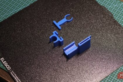 3D printed replacement clip designs resting on a printer build plate after testing AI-generated models