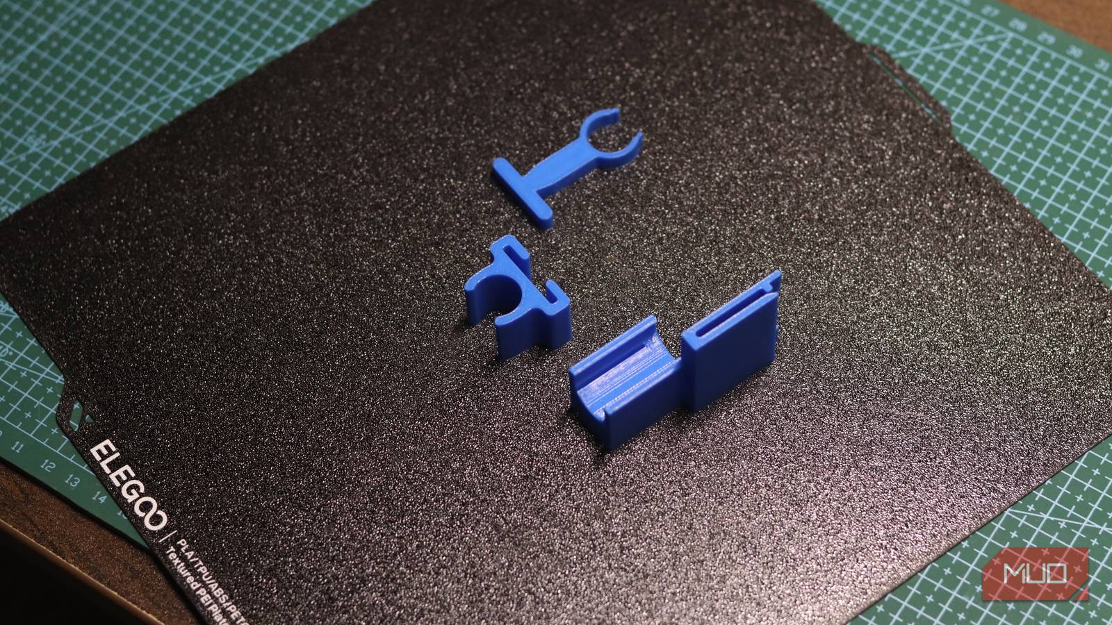 3D printed replacement clip designs resting on a printer build plate after testing AI-generated models