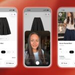 Person using a phone shopping app while comparing outfits on a clothing rack