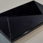 Nvidia Shield TV streaming box sitting next to a television remote