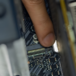 A hand unlatching a PCIe retention clip on a graphics card slot inside a desktop PC